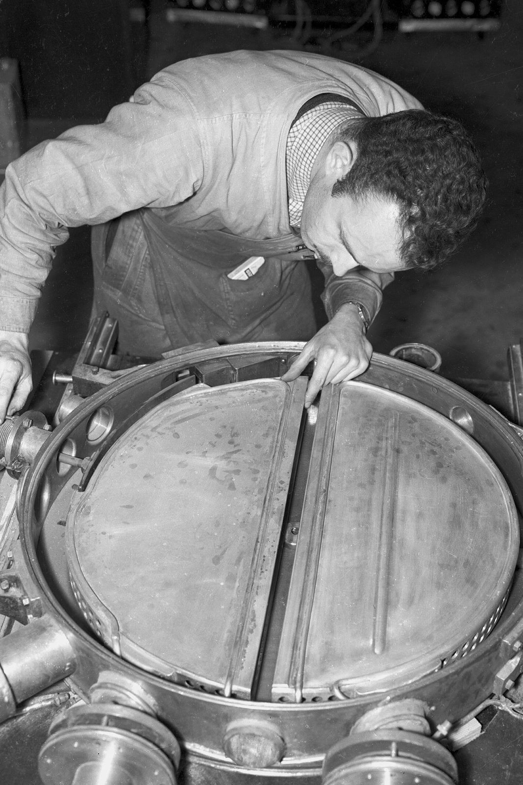 A 1930s cyclotron tank opened: a technician working between the giant copper dees.