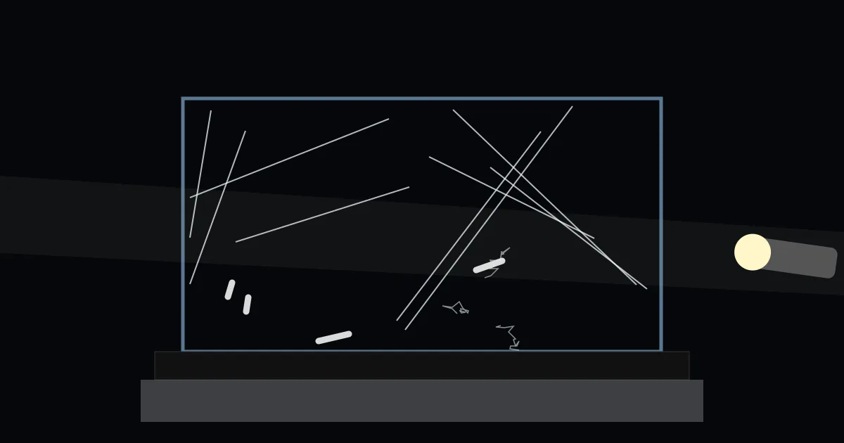 Illustration: a clear box sits on a black plate over dry ice, with thin white streaks and short thick tracks glowing in a flashlight beam inside.