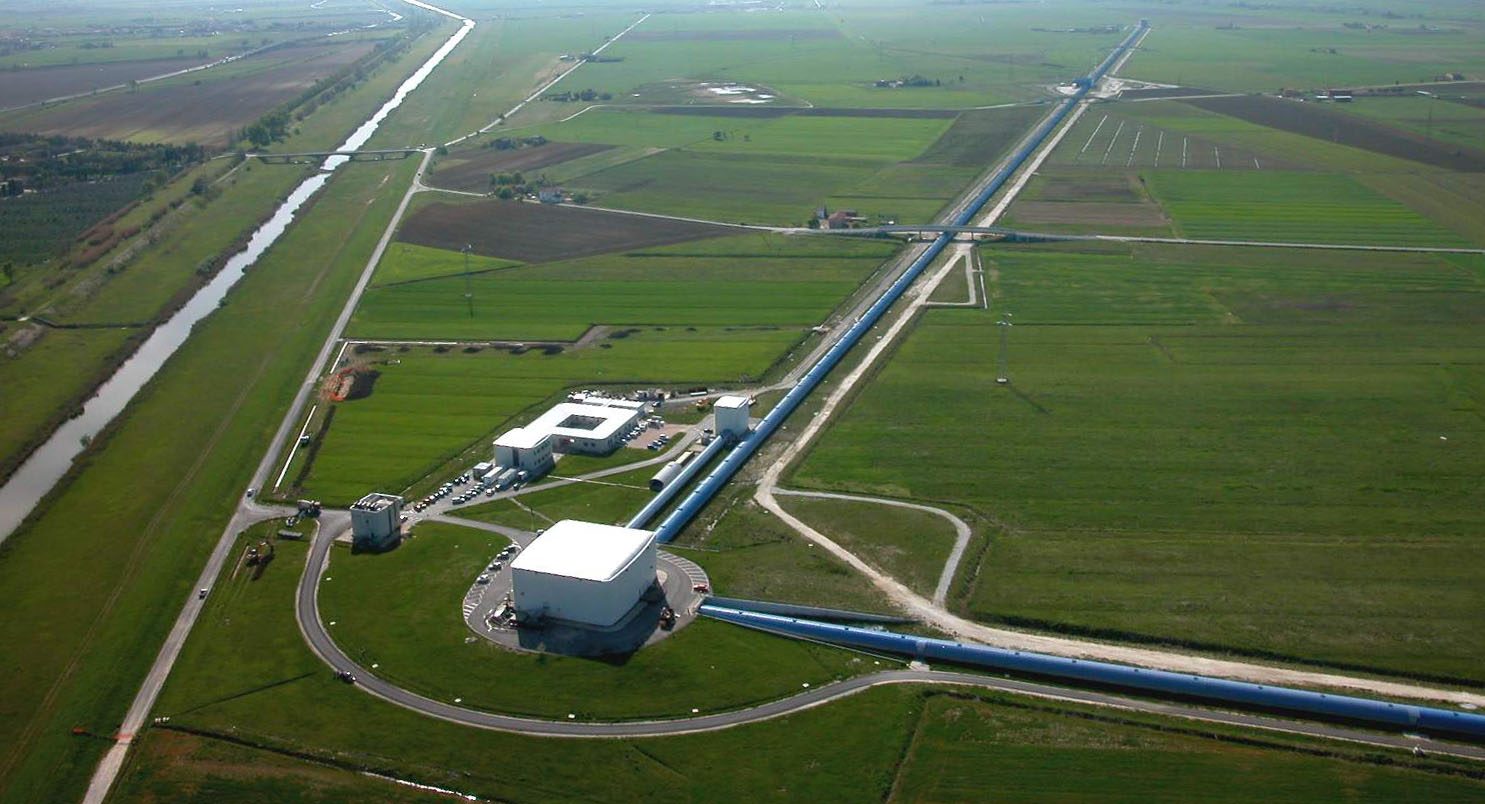 An aerial view of the Virgo gravitational-wave interferometer — two long arms meeting at a central building.