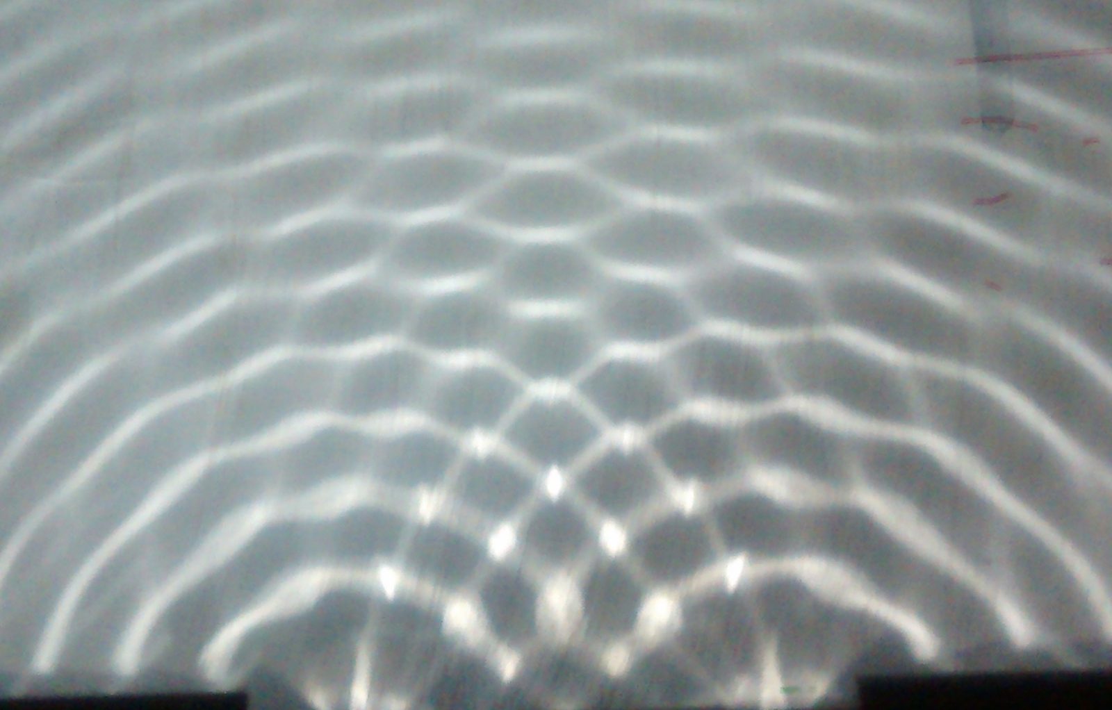 Two-source interference in a ripple tank — bright and dark bands radiating from two points.